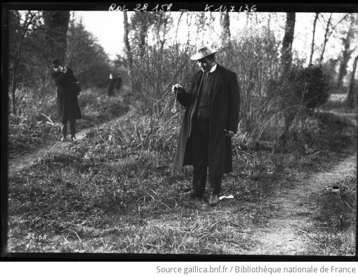 Radiestesista storico con pendolo nel bosco durante una ricerca d'acqua, fotografia del 1913